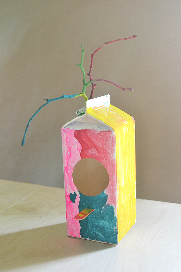 Adorable Milk Carton Bird Feeder Craft Using Twigs, Paints & Popsicle Sticks - Constructing a bird feeder out of a milk carton