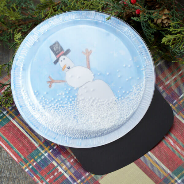 Fun To Make Plastic Plate Snow Globe Craft Project For Preschoolers - Create a snowman with a paper plate - a fun winter craft for kids. 