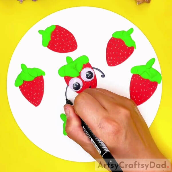 Pasting Googly Eyes-A fun fruit craft for children - paper and clay strawberries. 