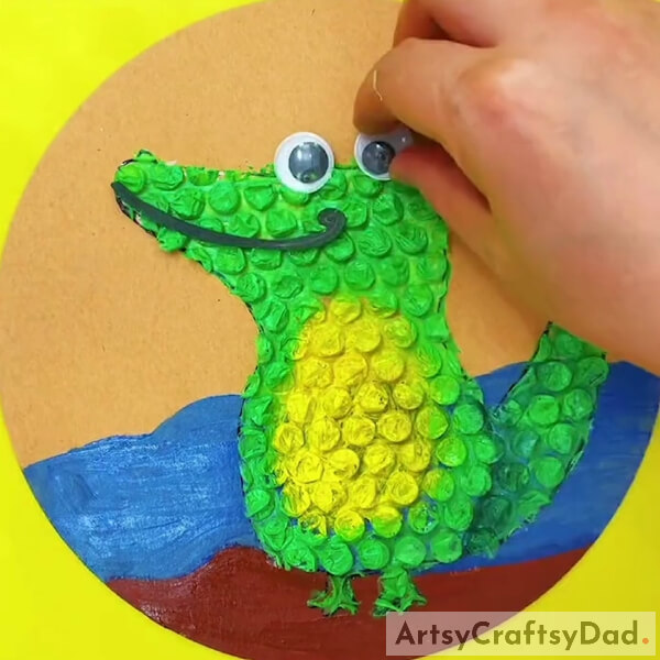 Adding Googly eyes- Learn to Create a Crocodile Art Piece with Bubble Wrap 