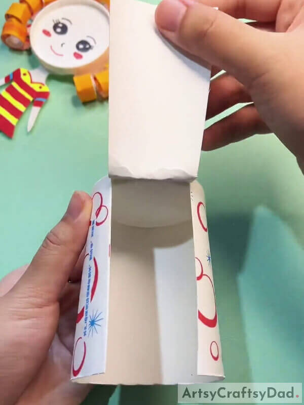 Cutting A Broad Strip From The Paper Cup- Crafting A Paper Cup Activity For Kids With Curly Hair
