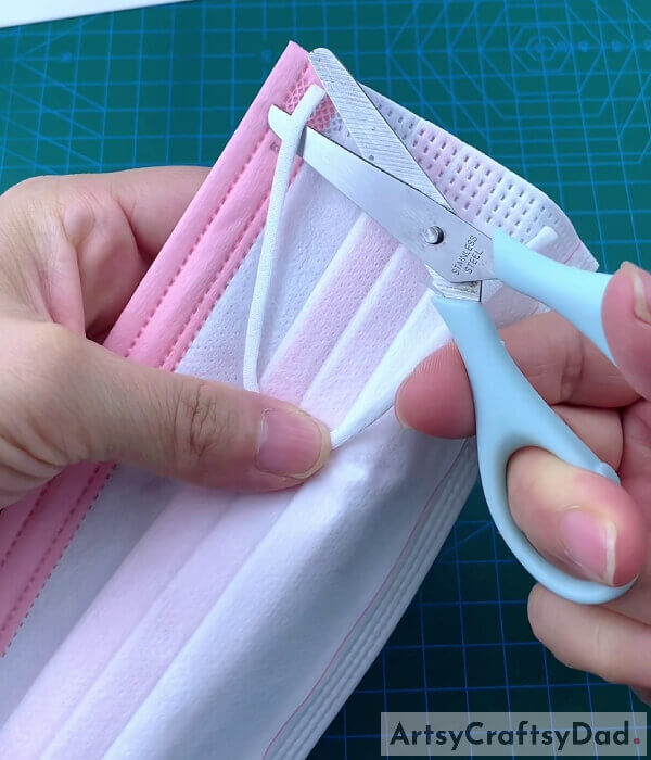 Cutting The Elastic Strap Of Surgical Mask Using Scissors- Learn how to make a pocket for a surgical mask. 