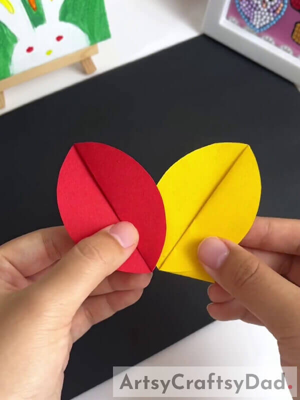 Inserting The Yellow Petal In The Red One - A how-to for making a paper pinwheel flower craft with children 