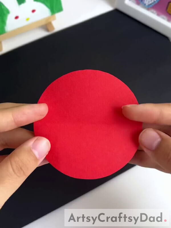 Making A Crease On Red Circle - How to make a paper pinwheel flower craft with kids 