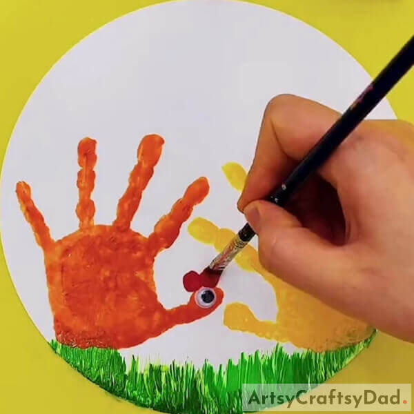 Now take some red paint and a googly eye - Crafting Paintings of Chickens with Handprints