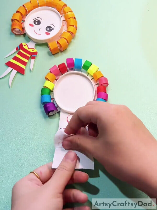 Peeling Off The Pattern Cover Of Cup- Learn How To Create A Paper Cup Craft With This Tutorial For Little Ones With Curly Hair