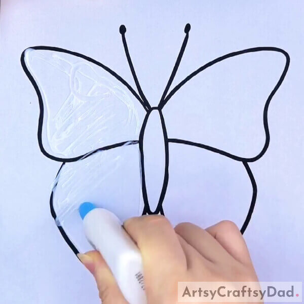 Applying Glue On The Wings Of Butterfly- Learn How to Craft a Colorful Butterfly with Tissue Paper and a Pen