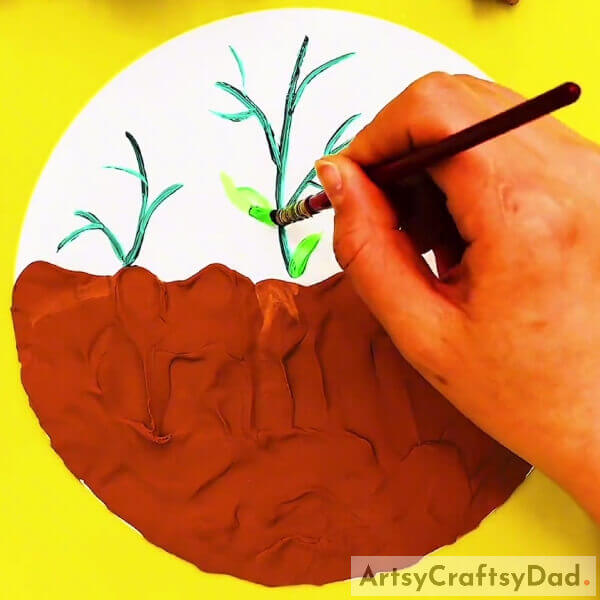 Drawing Leaves For Each Plants Using Green Paint- A Tutorial On How To Create A Piece Of Art Using Clay & Peanut Shells With Roots In The Ground