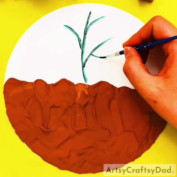 Drawing Plant Stems Using Dark Green Acrylic Paint- Making An Artwork Utilizing Clay & Peanut Shells That Have Their Roots In The Dirt