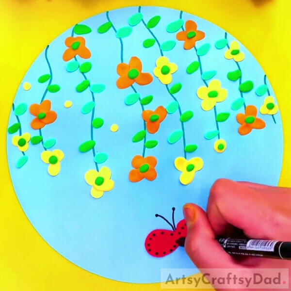Drawing Some Details Using A Black Marker - Orange-Yellow Flower Climber Clay Craft For Kids