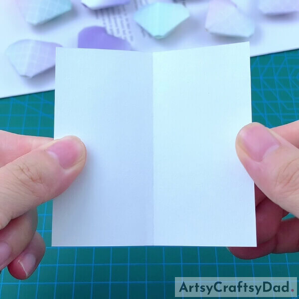 Folding Origami Paper Into Half- Step-by-step instructions on how to make an origami heart using paper for children