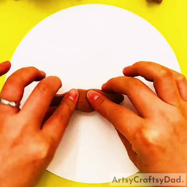 Pasting Brown Color Clay On White Craft Paper- Creating Art With Clay & Peanut Shells That Have Their Roots In The Earth 