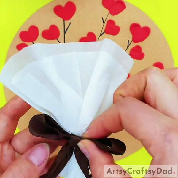 Securing The Bouquet Sleeve With A Bow- Making a Bouquet of Heart Shaped Flowers from Clay and Tissue - Tutorial