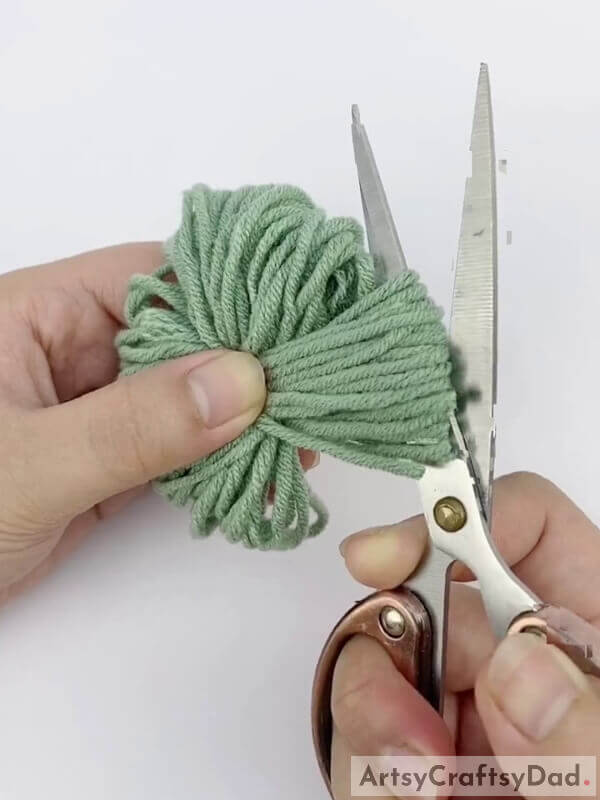 Cut the folds using a pair of scissors - Learn the Technique of Making Pom-Pom Blooms Out of Wool Thread