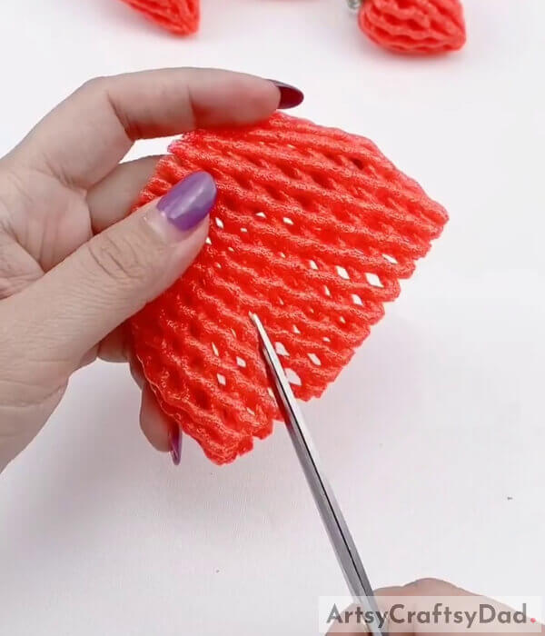 Make a small, diagonal, cut using a pair of scissors - Constructing a Foam Strawberry