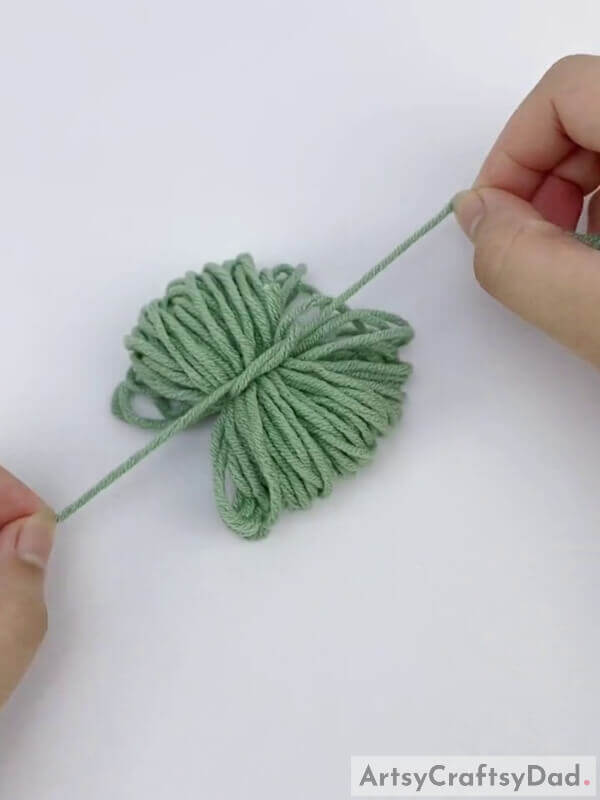 Now tie the bundle with a knot - Crafting Pom-Pom Blossoms with Wool Thread