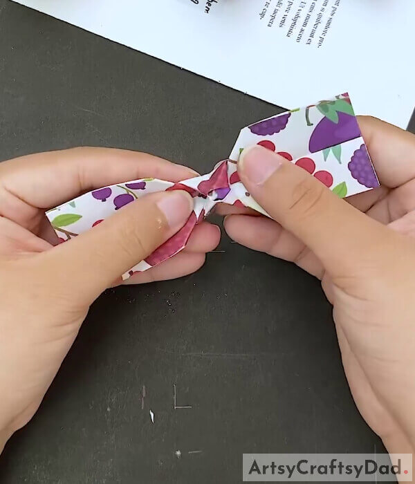 Open The Sides - Learn how to assemble a paper bow out of origami with this guide for kids