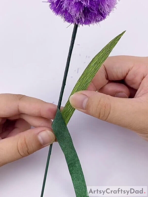 Place the leaf on that lower portion - Crafting A Ribbon Pom-Pom Flower For The Little Ones: A Tutorial