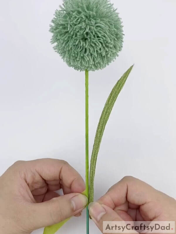 Take a green sheet of paper and make a leaf - Making Decorative Pom-Pom Flowers with Wool Thread