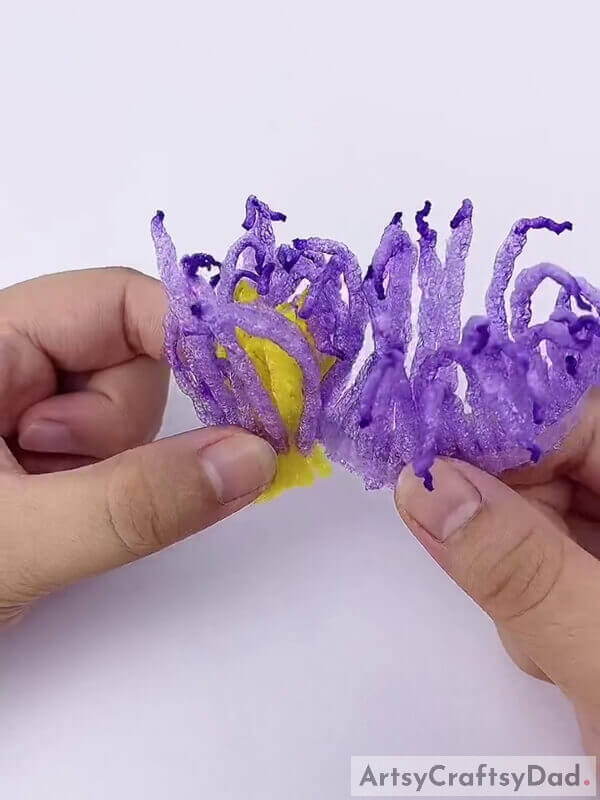 Wrap the purple strands around the yellow ones - Tutorial on using netting and purple fruits to decorate a craft 