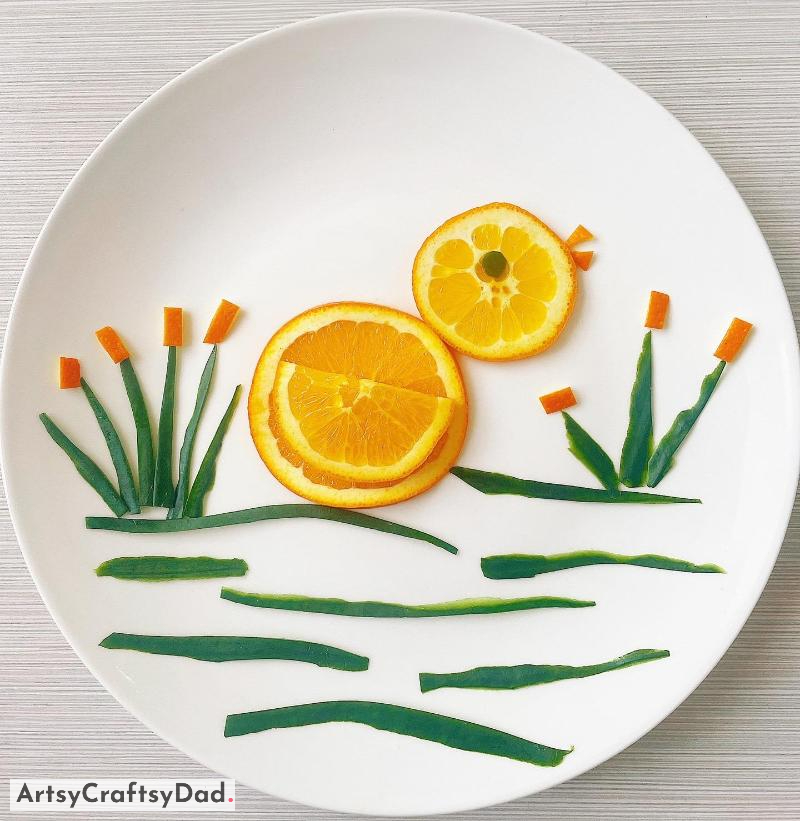 Orange Duckling around Cucumber Pond Food Decoration - A Duckling of Orange Colour beside a Pond of Cucumbers adorning a Meal