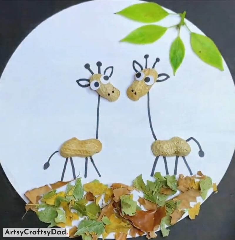 Peanut Shell Giraffe on Dried Leaves Ground Craft Idea - Artistic Projects Made with Recyclables on a Circular Shape