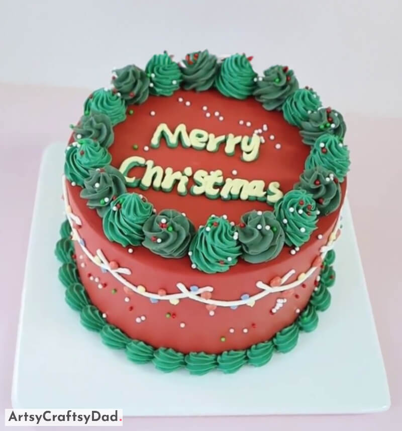 Red and Green Cake Decoration With Merry Christmas Written on the Top - Festive Cake Decoration Featuring a Tree and Snowman Topper