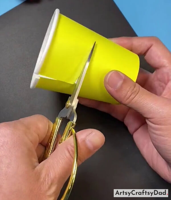 Cutting A Yellow Color Paper Cup