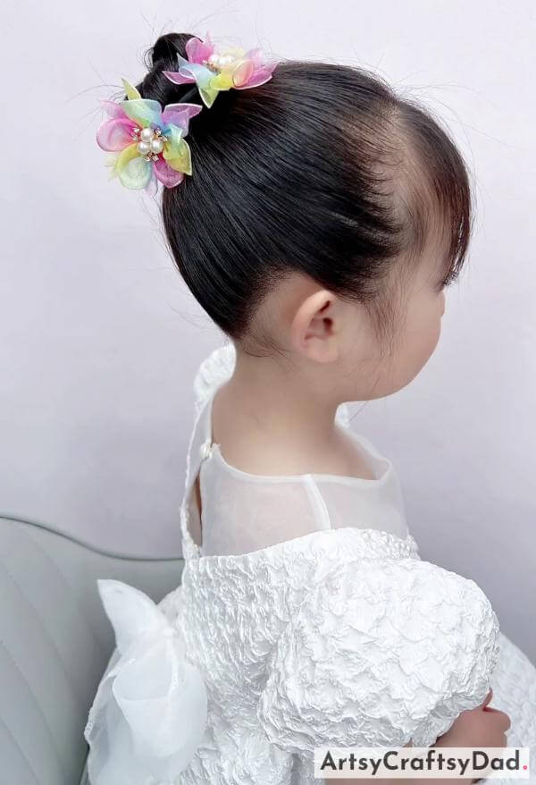 A Cute Bun Hairstyle with Flower Clips-Children's hairstyle featuring a braided bun and cute hair accessories.