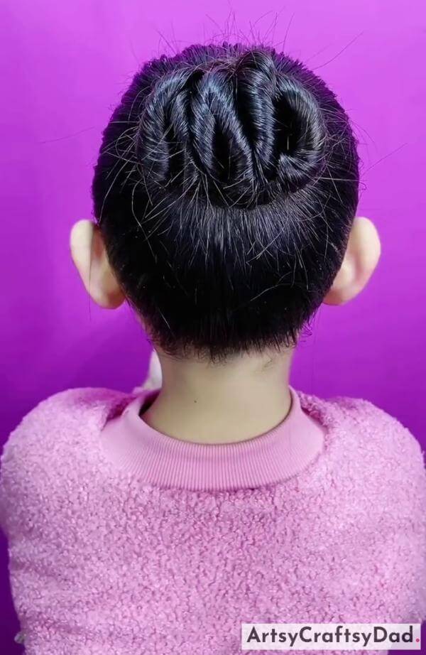 A Messy Twisted Bun Hairstyle for Kids-Cute hair clips to accessorize a kids' braided bun.