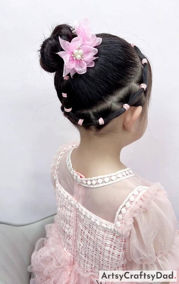 A Pink Beaded Flower Design Bun Hairstyle for Kids-Children's braided bun hairstyle with delightful hair accessories.