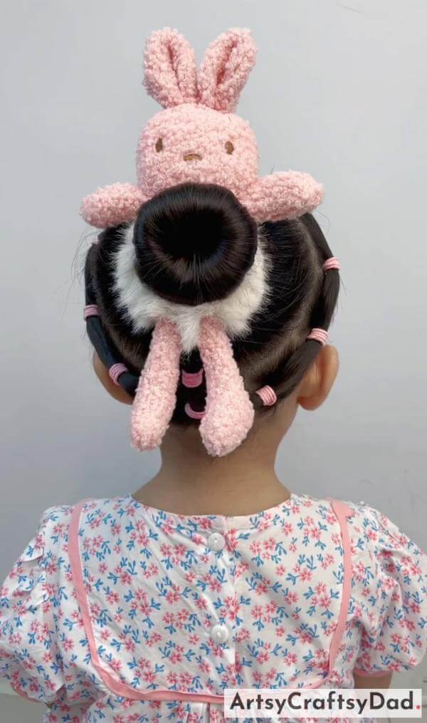 A Round Braided Bun Hairstyle With Toy Rubber Band-Sweet hair clips for a bun hairstyle on kids.