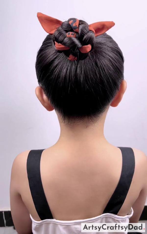 A Top Ribbon Bun Hairtsyle for Kids-Charming hairclips paired with a braided bun hairstyle for kids.